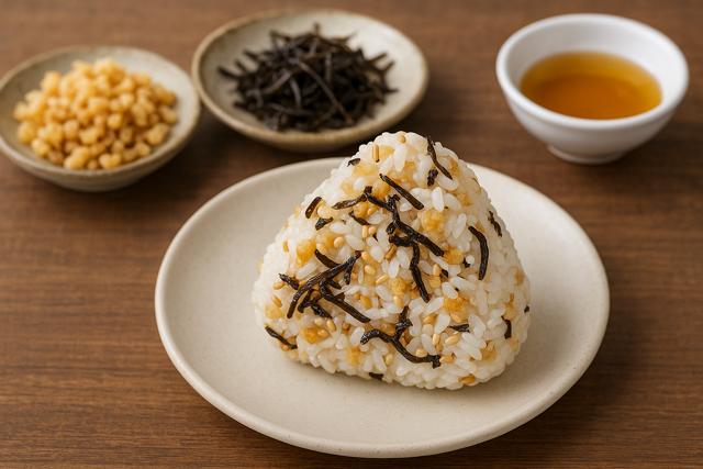 apanese rice ball, or onigiri, made with tempura bits, shredded kombu, and sesame seeds, accompanied by ingredients and sesame oil on a wooden table